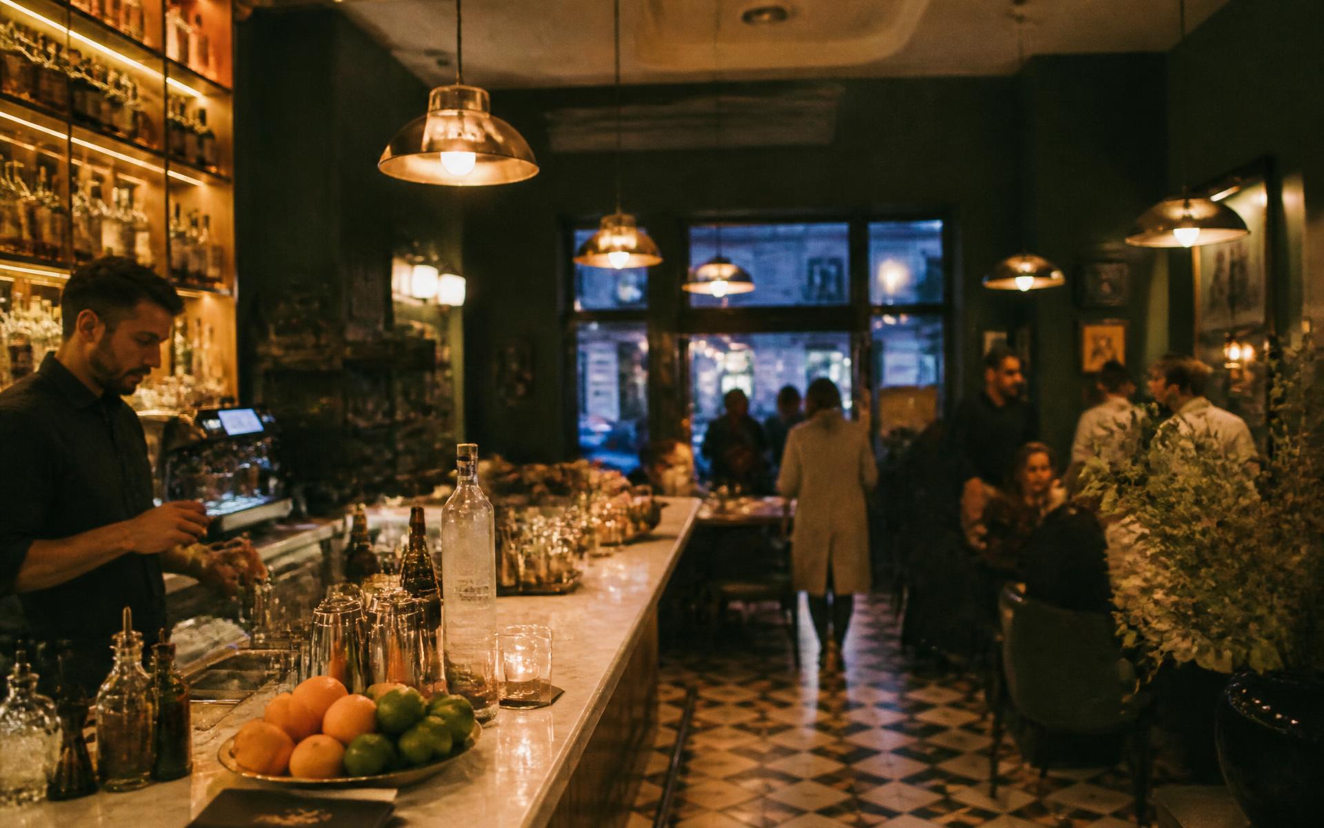Salle du bar restaurant en soirée, comptoir en marbre et lampes en laiton