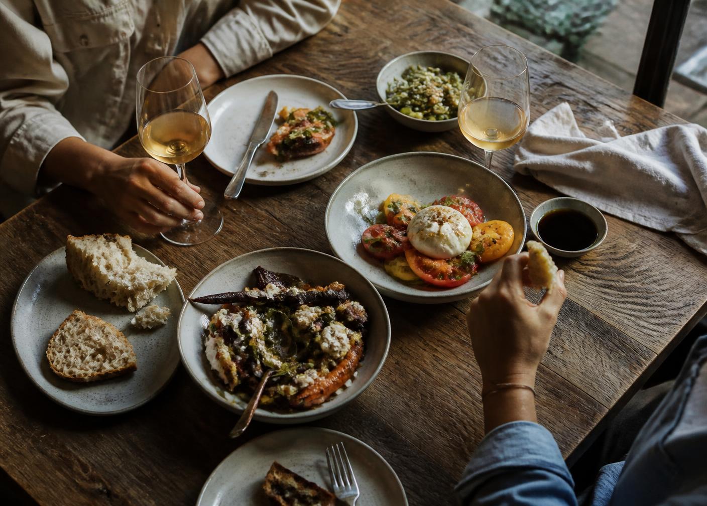Table partagée avec assiettes de saison, pain et vin blanc